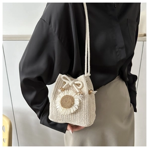 Detailed view of cream straw bucket bag featuring woven sunflower and rope drawstring closure