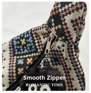 Detail of ethnic woven bag with colorful embroidery, smooth zipper, and plush monster charm
