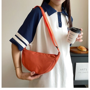 Close-up of orange nylon crescent bag worn by model in a casual lifestyle setting