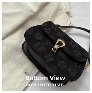 Close-up of black crossbody bag with 3D floral texture and gold buckle