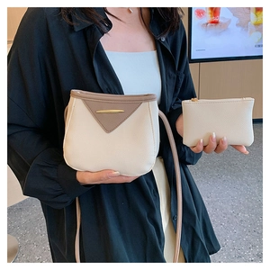 Detail of cream crossbody bucket bag with brown trim and gold buckle, including coin pouch