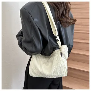 Detail of cream nylon pleated bag with round pouch and black adjustable strap