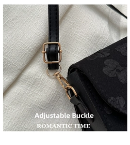 Close-up of adjustable golden buckle and floral texture on black shoulder bag strap