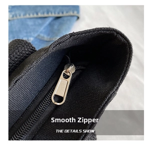 Close-up of smooth silver metal zipper on a black large capacity canvas tote bag