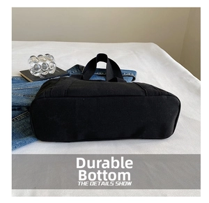 Close-up of durable reinforced bottom stitching on a large black canvas tote bag