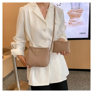 Chic beige textured leather bucket bag and pouch set on a white blazer model