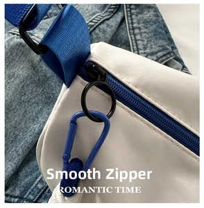 Detailed close-up of smooth zipper hardware and blue contrast strap on white crossbody bag