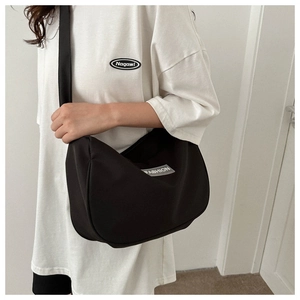 Détail d'un sac bandoulière en nylon noir avec étiquette mode porté par un mannequin
