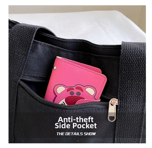 Detail shot of the hidden anti-theft side zipper pocket on a large black canvas tote bag