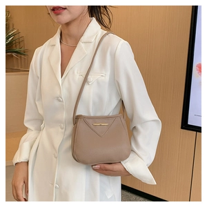 Close-up of beige lychee leather bucket bag with gold metal trim and triangle stitching