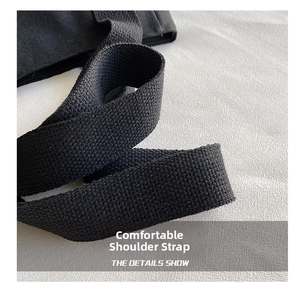 Macro view showing the durable black woven texture shoulder strap of a canvas tote bag
