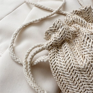 Elegant beige woven drawstring bucket bag with a natural textured finish and craftsmanship
