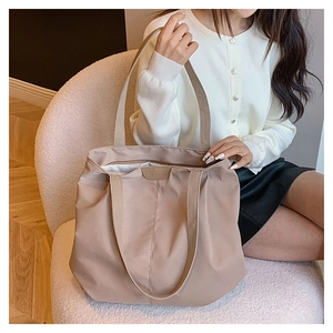 Détail du sac cabas en toile avec larges bandoulières et écusson logo en cuir