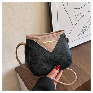 Detail of lychee textured crossbody bag with gold metal trim and beige V-shape piping