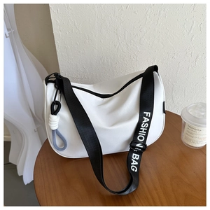 Detail of white half-moon crossbody bag with FASHION BAG strap and knot charm