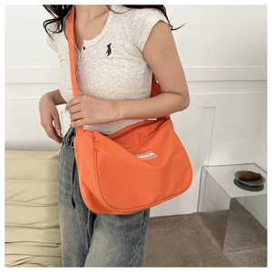 Dettaglio della borsa a tracolla arancione brillante in nylon impermeabile con logo