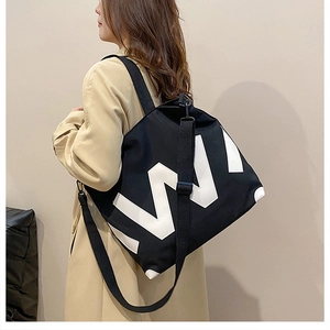 Détail du sac cabas en toile noire avec imprimé graphique et bandoulière réglable
