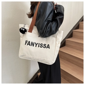 Detail of canvas tote bag with FANYISSA lettering and black soot sprite charm