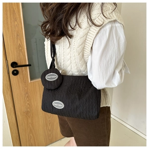 Detail of black pleated nylon crossbody bag with matching round pouch worn by a model