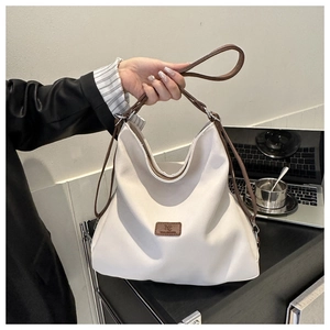 Close-up of cream canvas hobo bag with brown straps and leather MC logo patch