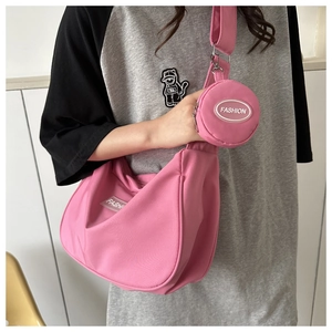 Détail du sac à bandoulière en nylon rose avec un petit porte-monnaie rond sur la sangle