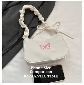 Détail du sac baguette blanc avec broderie papillon rose et bandoulière à volants