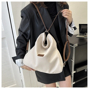 Detail of soft cream faux leather shoulder bag with adjustable brown strap and logo patch