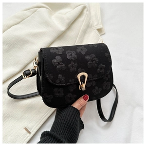 Close-up of black floral embroidery and gold U-shaped buckle on small crossbody bag