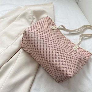 Pink logo tote bag with cream leather trim and gold studs on a soft white background