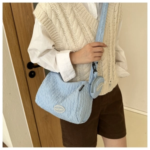 Detail of light blue quilted crossbody bag featuring a matching round coin purse attachment