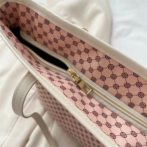 Cream tote bag showing golden zipper closure and pink patterned lining detail