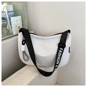 Close-up of white saddle bag with a black fashion-printed strap and knot pendant