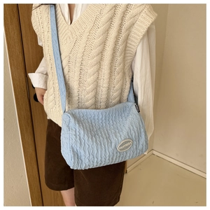Close-up of light blue smocked crossbody bag with FANYISSA logo and soft fabric texture