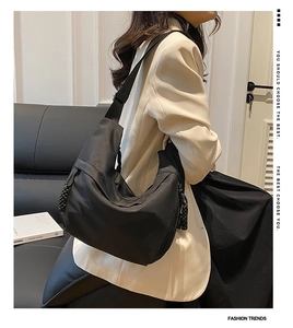 Detail of black nylon crescent hobo bag with braided knot zippers on a stylish model