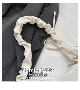 Détail du sac blanc avec poignée froncée, anneaux dorés et tissu synthétique souple