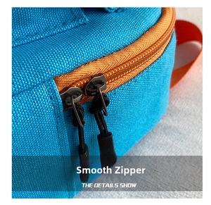 Détail des doubles fermetures éclair orange sur un mini sac à dos en toile bleue