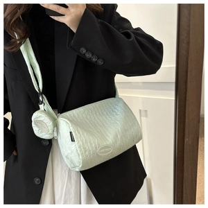 Detail of mint green quilted cylinder shoulder bag with round coin purse and metal tag