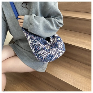 Detail of ethnic geometric woven crossbody bag with vibrant blue nylon strap on stairs