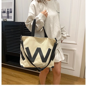 Détail du sac fourre-tout en toile avec écusson W noir et bandoulière réglable