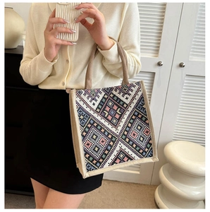 Detail of colorful geometric embroidery on canvas tote bag with brown handles