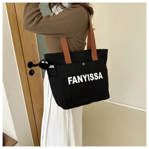Detail of black canvas tote bag with FANYISSA print and brown shoulder straps
