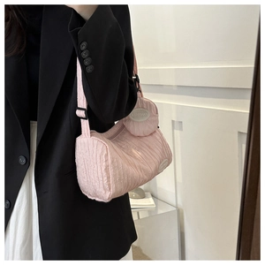 Detail of pink pleated crossbody bag with matching round pouch and black adjustable strap