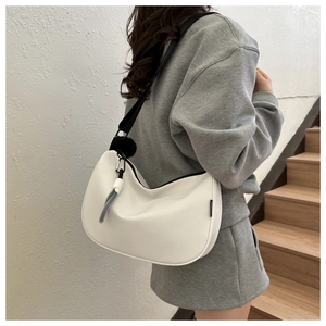 Detail of white half-moon hobo bag with contrast black strap and knot charm accessory