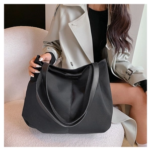 Détail du grand sac cabas noir avec poignées en cuir et couture verticale sur la toile