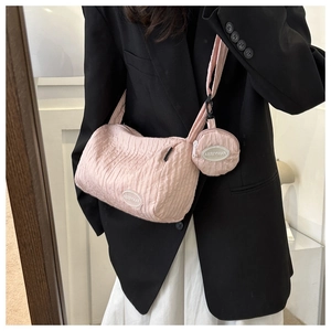 Pink pleated nylon dumpling bag with matching round pendant charm on model shoulder