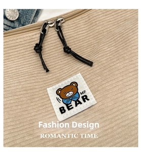 Detail of corduroy bag featuring a double zipper and a cute embroidered bear patch