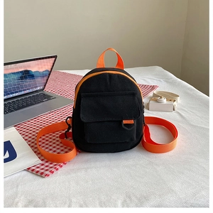 Détail d'un mini sac à dos noir et orange avec des bretelles contrastées sur un bureau