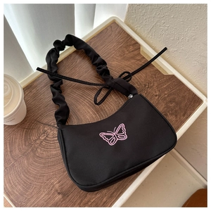 Détail du sac noir avec broderie papillon rose et bandoulière à volants froncés