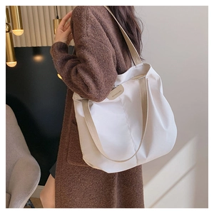 Détail du sac fourre-tout en toile ivoire avec sangles contrastées et écusson logo en cuir