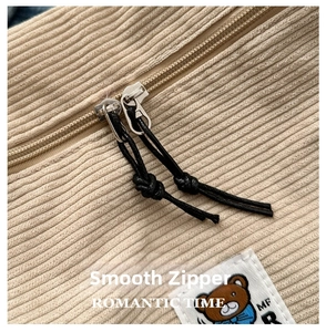 Detailed close-up of corduroy handbag featuring smooth dual zippers and a cute bear patch